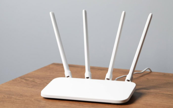 White WiFi router with four antennas on wooden table